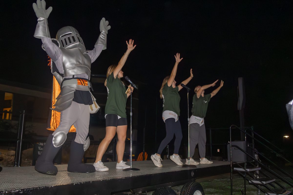 Sir Victor, accompanied by various orientation staff leaders dance on the stage as students gather on the lawn to kick off Outfly.
