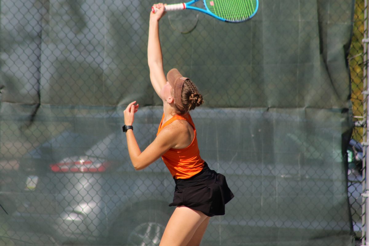 Senior Tori Johnson goes up for the serve at a meet on Sept. 27th at the Meirink Family Tennis facility.