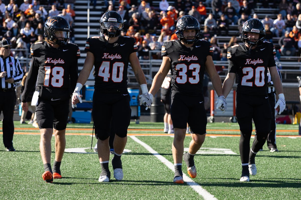 Senior football captains walk to the center of the field for the coin flip before the kickoff of the game.