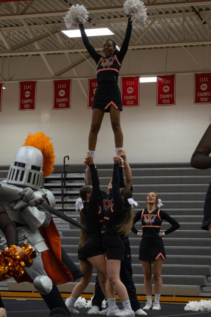 The Wartburg Cheer team performing a stunt with sir victor dancing. 