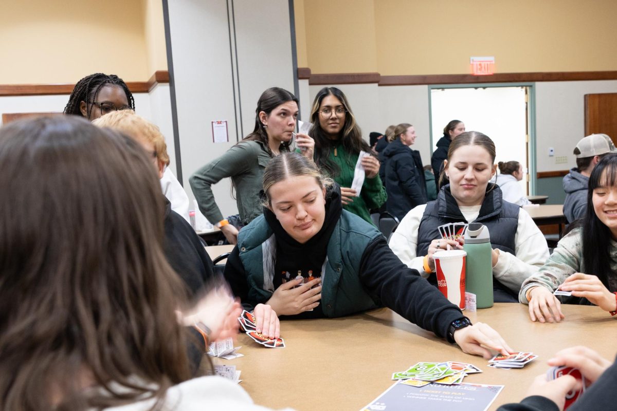 A student is picking up a card in the game of Uno after not having the current color. 