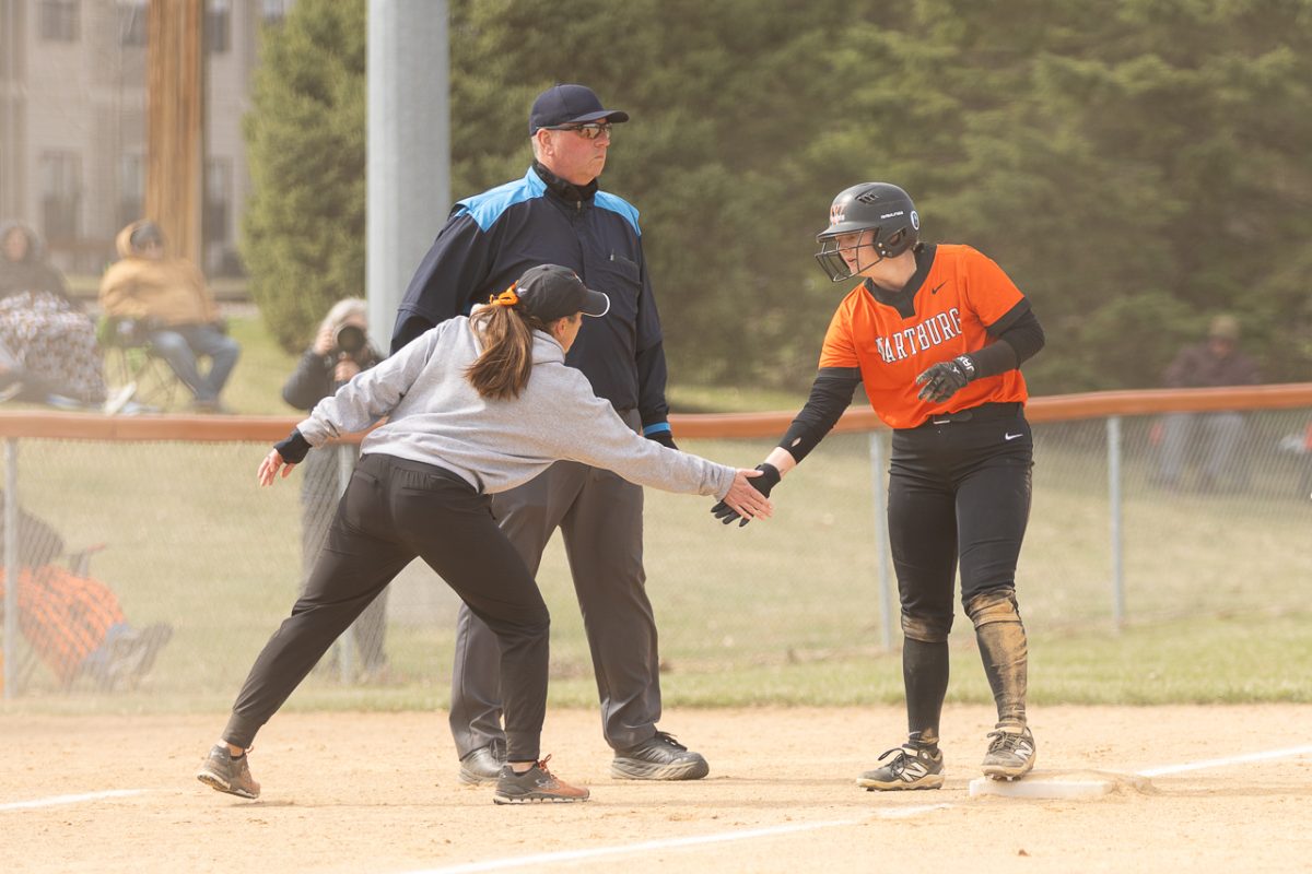 Head Coach Jamie Mueller high fives senior Jenna Wiebenga after making it safely to third base.  